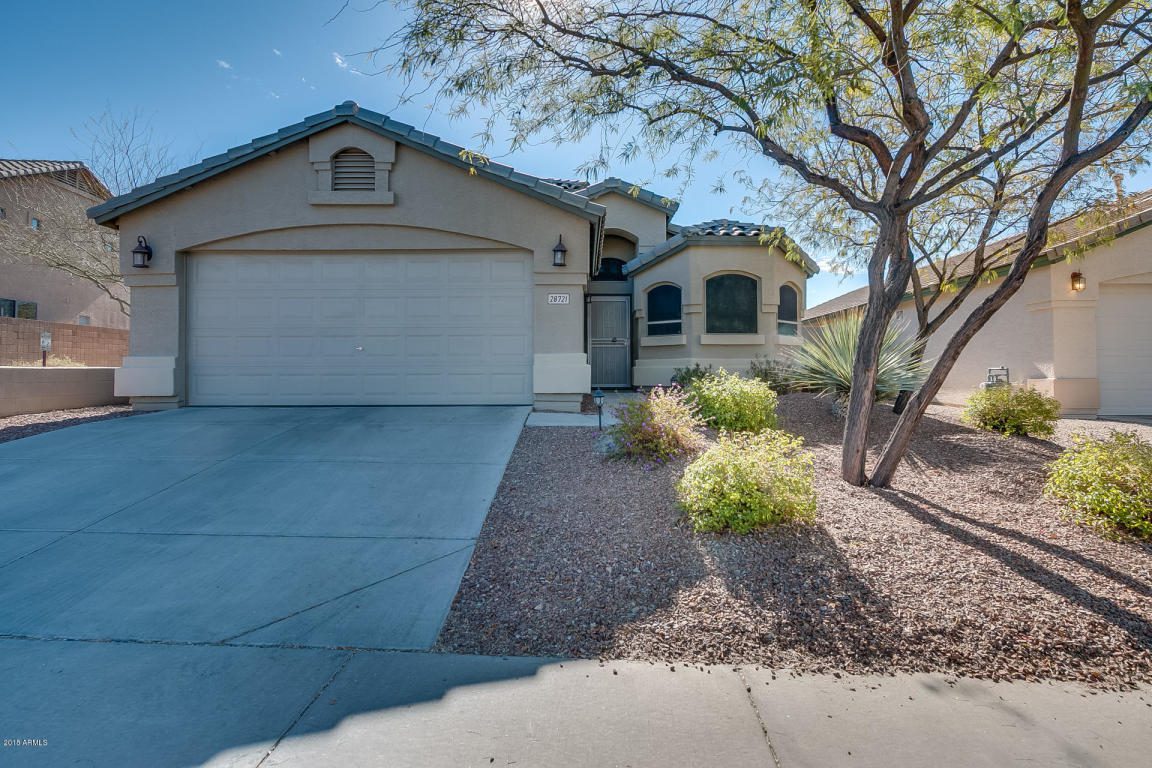 A driveway leading to a two-car garage and tiled-roof house, shaded by a tree in a neighborhood served by HomeQwik, experts in real estate in Arizona