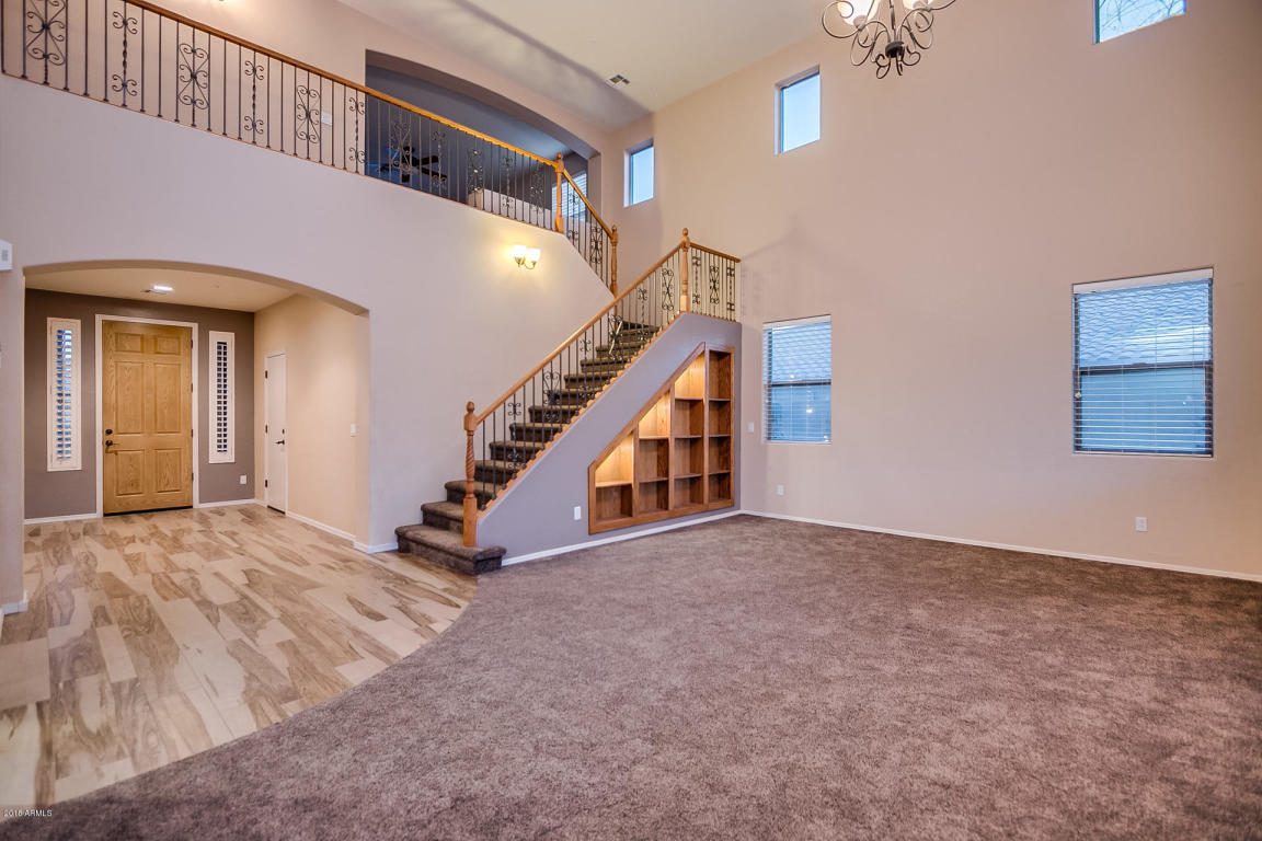 A beige living room with a wood-railed staircase in a neighborhood served by HomeQwik, experts in real estate in Arizona