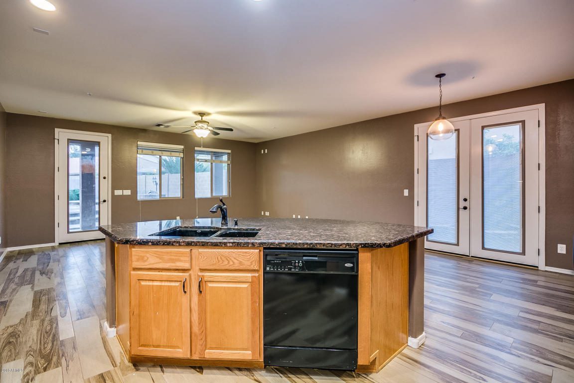 HomeQwik's homes for rent can have kitchens like this one, with a granite-top kitchen island in the middle of a brown room with faux wood floors